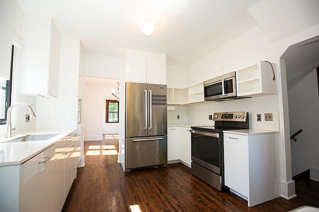 kitchen featuring appliances with stainless steel finishes, dark wood-style flooring, light countertops, open shelves, and a sink