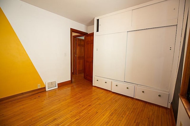 unfurnished bedroom with a closet, visible vents, baseboards, and light wood finished floors