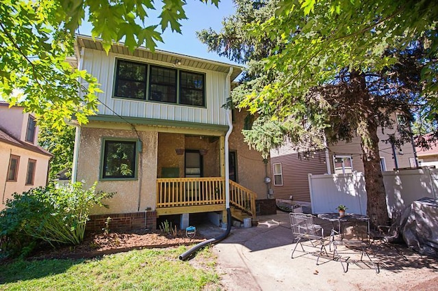 view of front facade with covered porch, a patio area, and board and batten siding