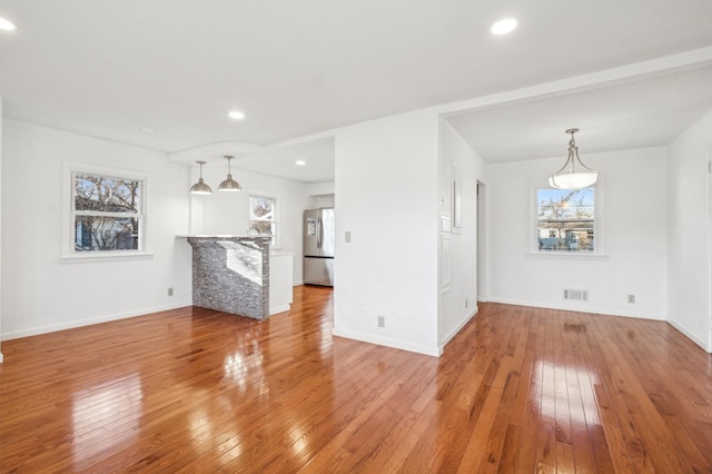 unfurnished living room featuring baseboards, light wood-type flooring, visible vents, and recessed lighting