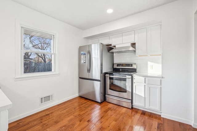 kitchen with stainless steel appliances, white cabinetry, visible vents, wall chimney range hood, and decorative backsplash