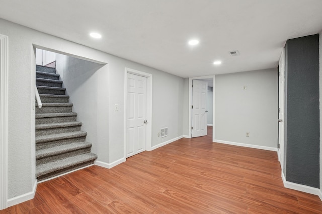 basement featuring stairs, wood finished floors, visible vents, and baseboards