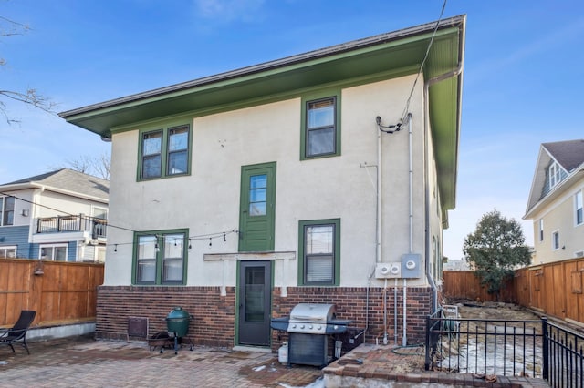 rear view of property with a patio, brick siding, and a fenced backyard