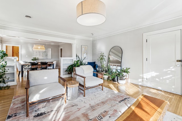 living room featuring wood finished floors, crown molding, and baseboards