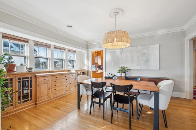dining area featuring crown molding, light wood-type flooring, a chandelier, and baseboards