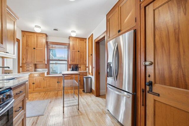 kitchen with stainless steel appliances, light wood-type flooring, a sink, and brown cabinets