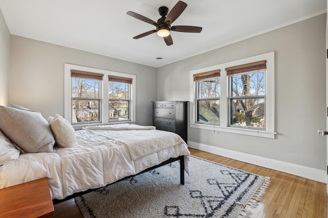 bedroom with multiple windows, baseboards, ornamental molding, wood finished floors, and a ceiling fan