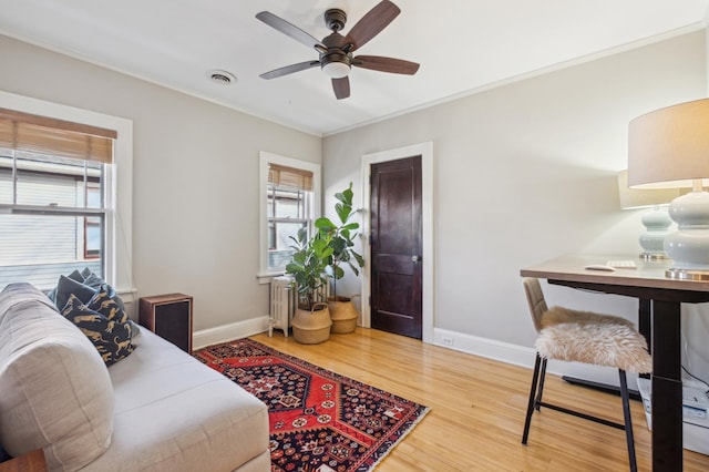 living room featuring baseboards, wood finished floors, healthy amount of natural light, radiator heating unit, and crown molding