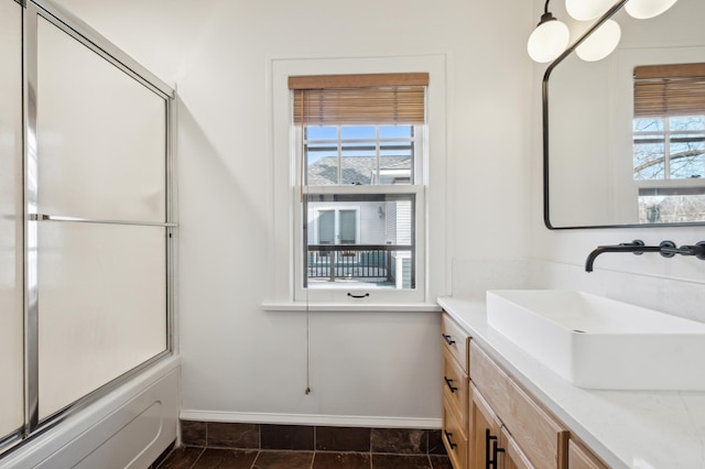 bathroom with baseboards, vanity, and shower / bath combination with glass door