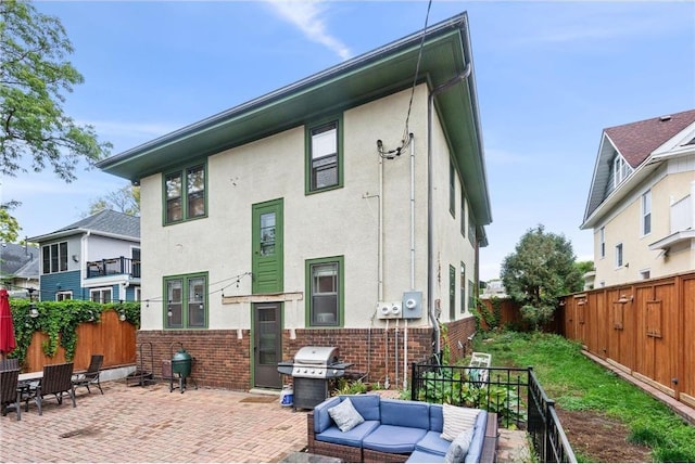 rear view of house featuring stucco siding, a patio area, a fenced backyard, and brick siding