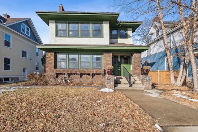 view of front of house with stucco siding, brick siding, and fence