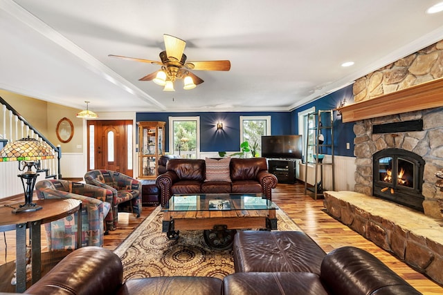 living area featuring stairs, crown molding, a wainscoted wall, wood finished floors, and a fireplace