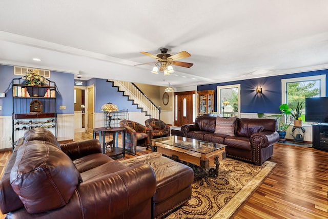 living area with stairway, hardwood / wood-style floors, visible vents, and a wainscoted wall
