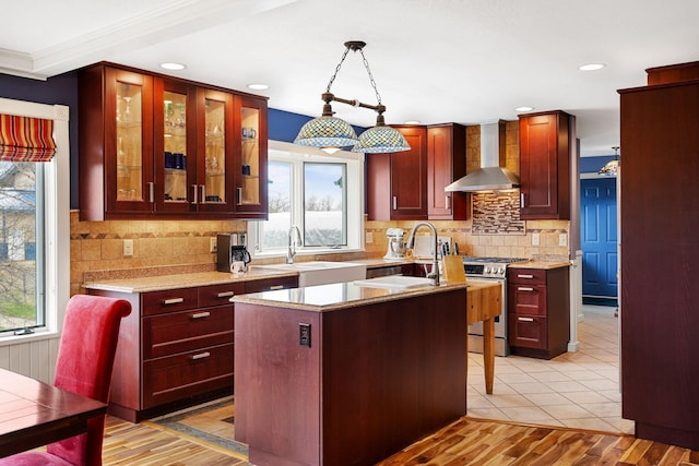 kitchen with stainless steel range with gas cooktop, wall chimney range hood, a sink, and dark brown cabinets