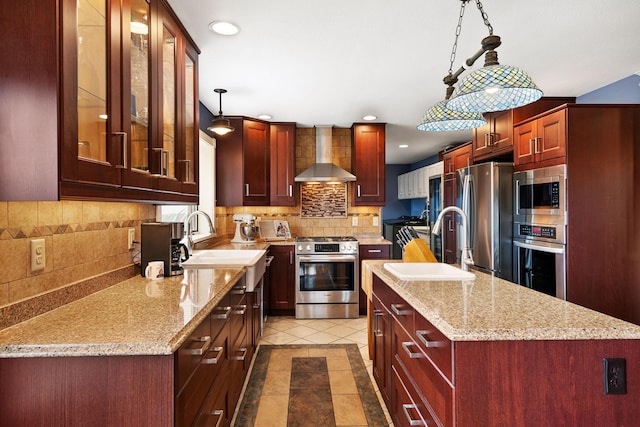 kitchen with dark brown cabinets, a sink, decorative backsplash, wall chimney range hood, and appliances with stainless steel finishes