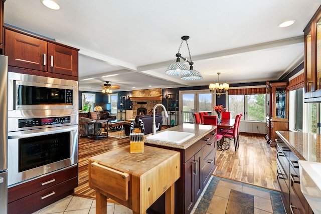 kitchen with recessed lighting, decorative light fixtures, a sink, beamed ceiling, and stainless steel appliances