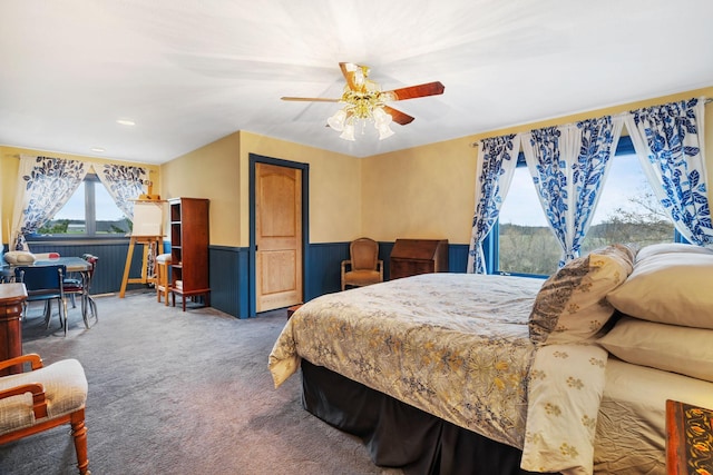 carpeted bedroom with a ceiling fan and wainscoting
