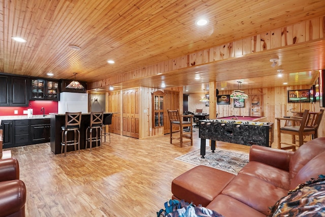 living area with light wood finished floors, wet bar, and wooden walls