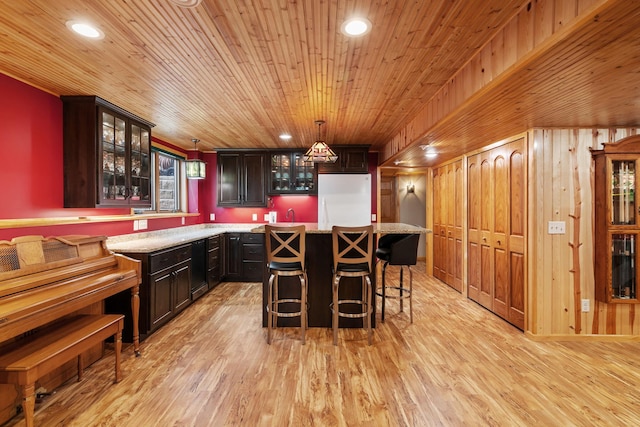 bar with freestanding refrigerator, wood walls, decorative light fixtures, light wood-style floors, and recessed lighting
