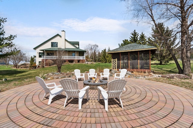 view of patio / terrace featuring an outdoor fire pit and a sunroom