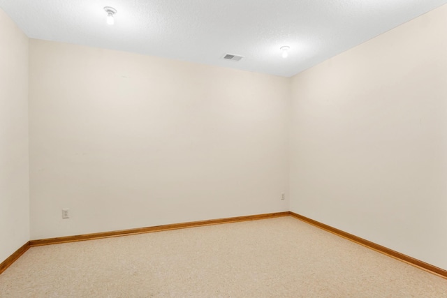 empty room with light carpet, baseboards, visible vents, and a textured ceiling