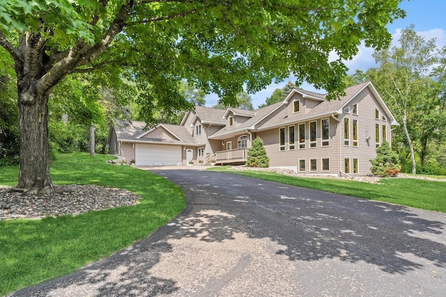 view of front facade featuring aphalt driveway, a shingled roof, and a front lawn