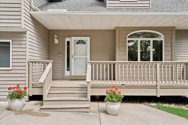 entrance to property featuring roof with shingles and covered porch
