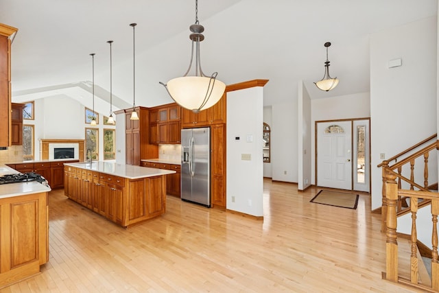 kitchen with brown cabinets, stainless steel fridge with ice dispenser, backsplash, and light wood-type flooring