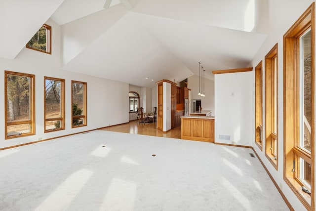 unfurnished living room with light colored carpet, baseboards, visible vents, and plenty of natural light