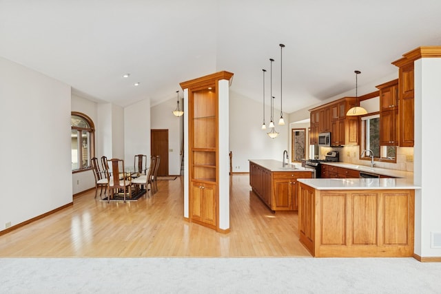 kitchen featuring a sink, stainless steel appliances, light countertops, baseboards, and lofted ceiling