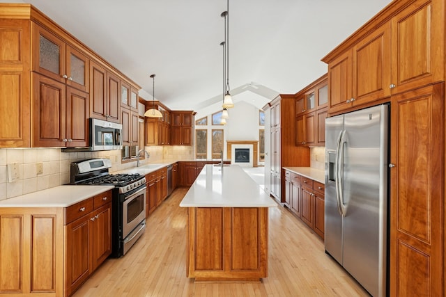 kitchen featuring vaulted ceiling, tasteful backsplash, a sink, light wood-type flooring, and stainless steel appliances
