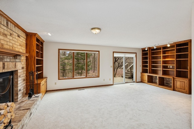 unfurnished living room with baseboards, a fireplace, a textured ceiling, built in features, and light colored carpet