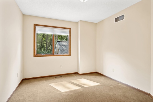 spare room featuring light carpet, visible vents, and baseboards
