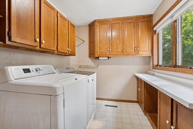 washroom featuring washing machine and dryer, baseboards, light floors, and cabinet space