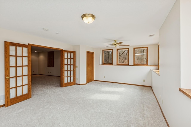 empty room with carpet flooring, baseboards, ceiling fan, and french doors