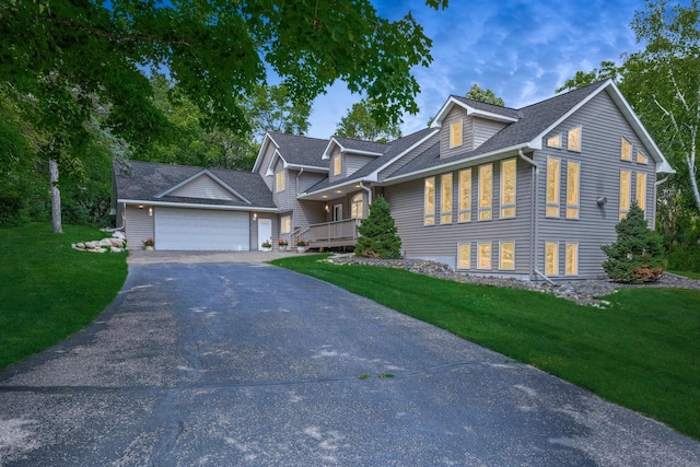 view of front of house with a shingled roof, aphalt driveway, a front yard, and a garage