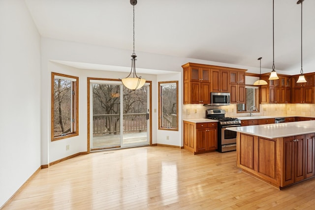 kitchen featuring light wood-style floors, brown cabinetry, appliances with stainless steel finishes, and decorative backsplash