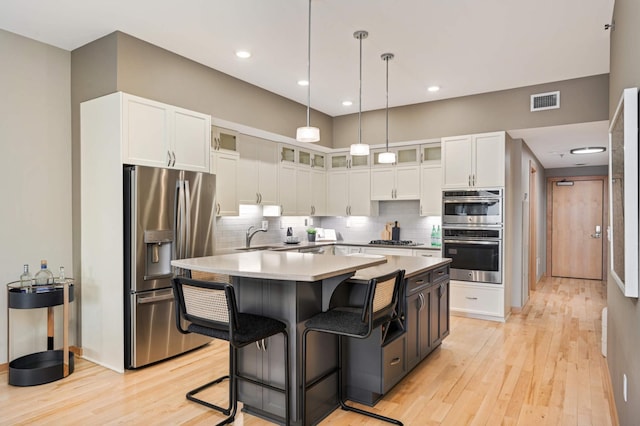 kitchen featuring tasteful backsplash, visible vents, appliances with stainless steel finishes, a center island, and white cabinetry