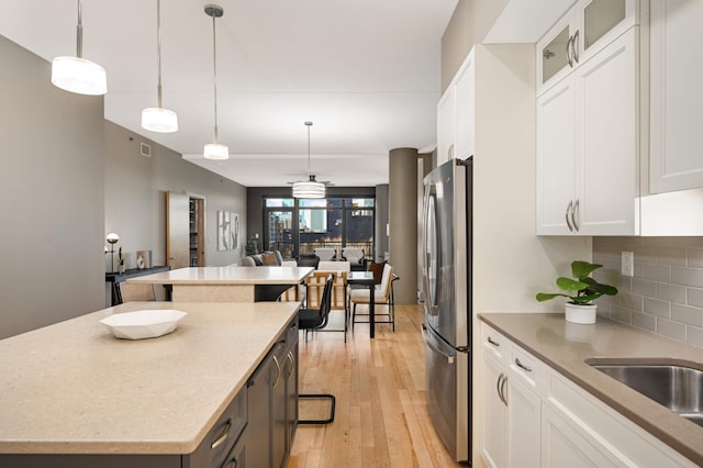 kitchen with decorative backsplash, open floor plan, a center island, freestanding refrigerator, and light wood-type flooring