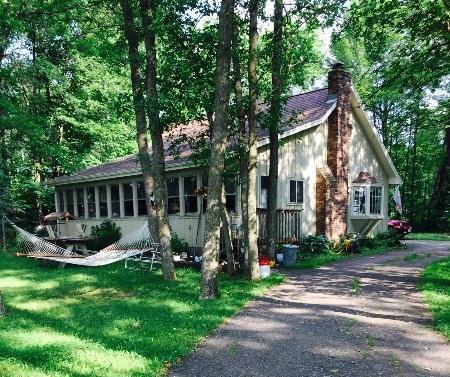 view of front of house featuring driveway, a chimney, a front yard, and a sunroom