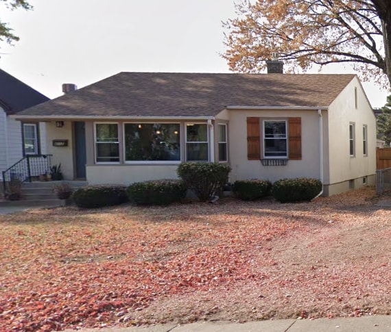 view of front facade featuring roof with shingles, fence, a chimney, and stucco siding