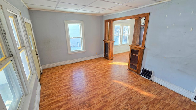 unfurnished room featuring a paneled ceiling, visible vents, baseboards, and wood finished floors