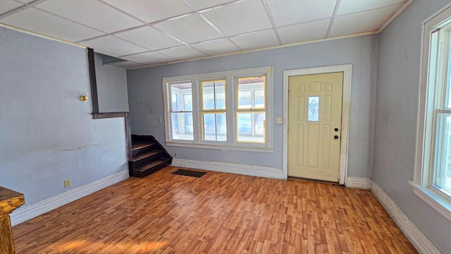 foyer entrance with a wealth of natural light, stairs, a paneled ceiling, and wood finished floors