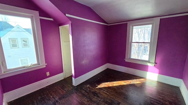 empty room with wood-type flooring, baseboards, and vaulted ceiling