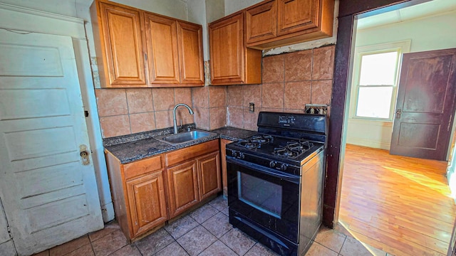 kitchen with gas stove, tasteful backsplash, brown cabinets, and a sink