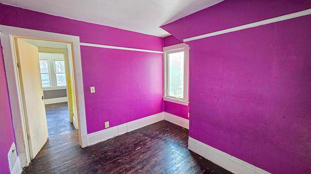 empty room featuring wood-type flooring, baseboards, and visible vents
