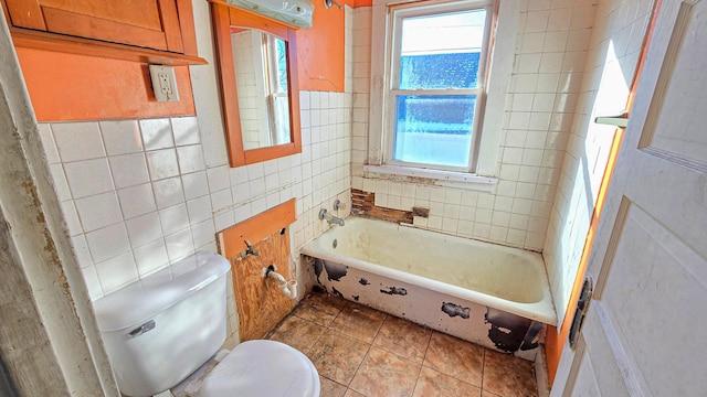 bathroom with tile walls, tile patterned floors, toilet, and a bath
