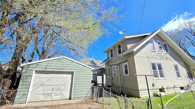 view of home's exterior with a detached garage, fence, and an outdoor structure