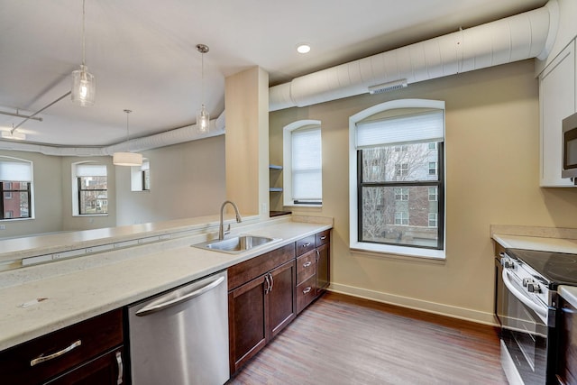 kitchen featuring appliances with stainless steel finishes, light wood-style floors, baseboards, and a sink