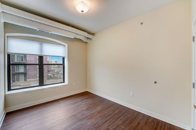 empty room with baseboards and dark wood finished floors